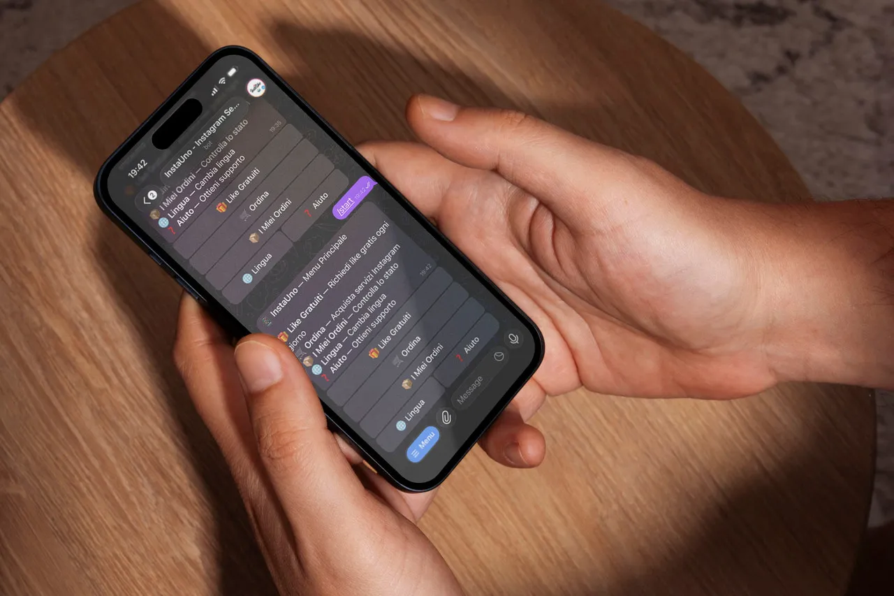 Due mani tengono uno smartphone con la chat del bot InstaUno aperta su Telegram